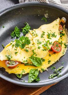 an omelet with tomatoes, cheese and herbs in a pan