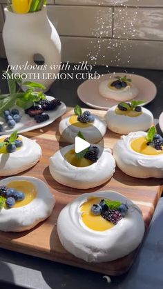 an assortment of appetizers are arranged on a wooden tray with flowers in the background