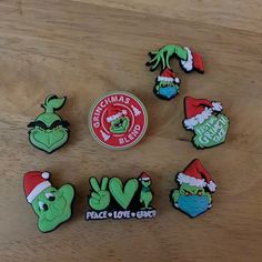 the grin's face pins are sitting on a wooden table next to a sticker that says peace love and santa hat