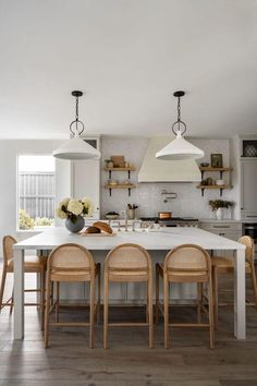 a kitchen with white counters and wooden chairs