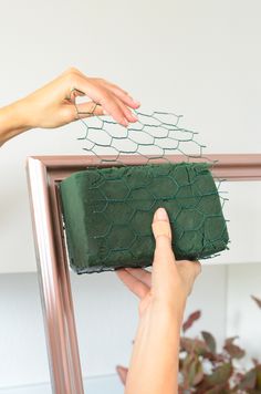 two hands reaching for a piece of green cake on a shelf with wire netting around it