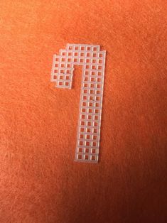 a cross made out of small squares on an orange surface with the letter t in it