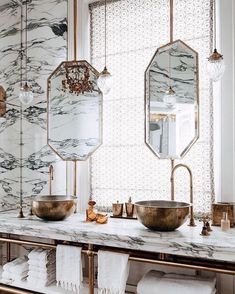 a bathroom with marble counter tops and gold fixtures on the wall, along with two large mirrors