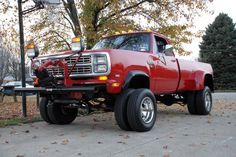 a red truck parked on the side of a road next to a street light and trees