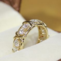 a close up of a ring with diamonds in it on a white cloth covered box