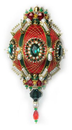 a red and green brooch with pearls on it's end, surrounded by other beads