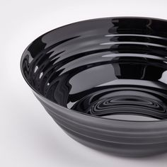 an empty black bowl on a white surface