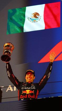 the man is holding up his trophy in front of two flags and a mexican flag