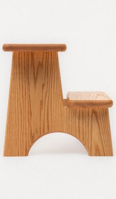 a small wooden chair sitting on top of a white floor next to a stool that is shaped like a footstool