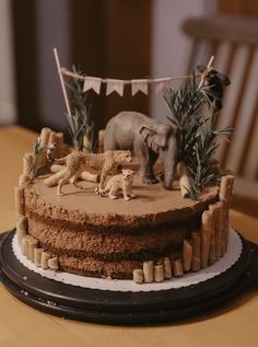 there is a cake that has animals on it and decorations around the top, along with an elephant figurine