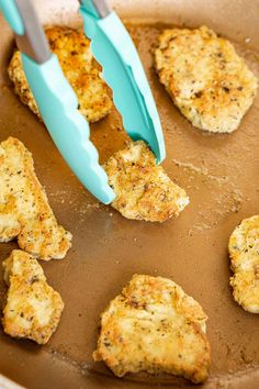 some chicken patties are being cooked in a skillet with a blue spatula