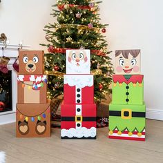 three cardboard christmas boxes sitting in front of a christmas tree