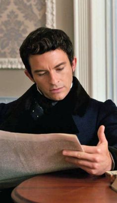 a man sitting at a table reading a paper