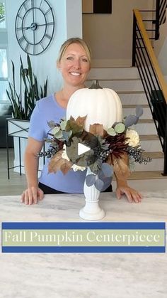 a woman sitting in front of a white pumpkin on top of a table next to stairs