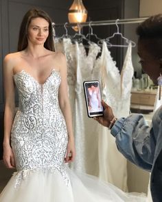 a woman in a wedding dress holding up a cell phone