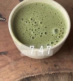 a cup filled with green liquid sitting on top of a wooden table