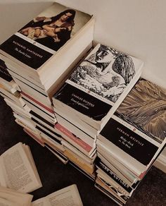 a stack of books sitting on top of a floor next to a wall with pictures