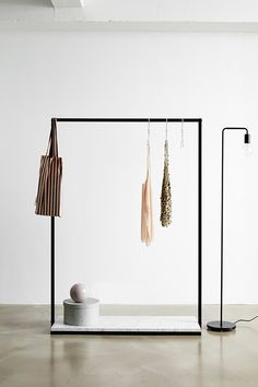 an empty room with clothes hanging on the rack and two lamps next to each other