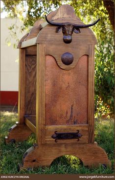 an old wooden box with a bull head on it's top and bottom, sitting in the grass