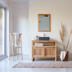 a bathroom with a wooden cabinet, mirror and rug in front of the window on the floor