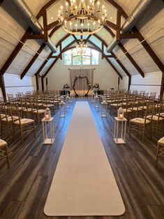 an empty church with rows of chairs and a white aisle leading up to the alter