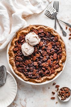 a pecan pie with ice cream on top and two spoons next to it