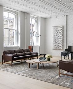 a living room filled with furniture and a piano in front of two large open windows