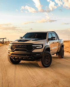 a silver truck driving down a dirt road