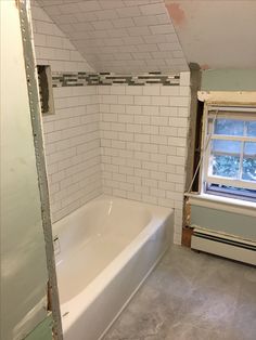 a bathtub and window in a bathroom being remodeled with white tiles on the walls