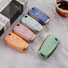 four cell phones sitting next to each other on a marble counter top with an open book in the background