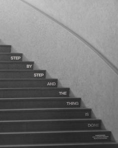 black and white photograph of stairs with handrails that read step by step and the thing is done