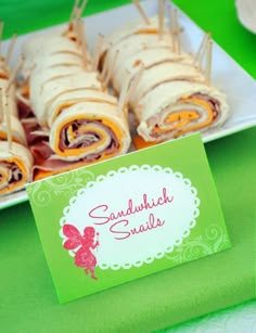 there is a plate full of sandwiches and place cards on the table for guests to eat