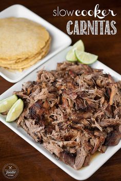 two plates filled with meat and tortillas on top of a wooden table next to each other