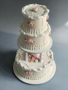 three tiered wedding cake with pink flowers on the top and white trimmings