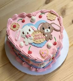 a pink heart shaped cake with teddy bears and hearts on the top is sitting on a plate