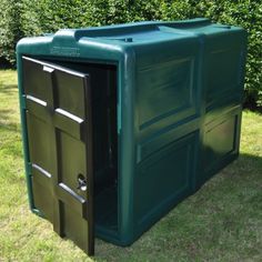 a large green box sitting on top of a lush green field next to a hedge