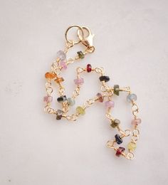 Spread creativity and joy with this multicolor gemstone Tourmaline bracelet! This handmade beauty features natural Tourmaline crystals in a variety of hues, including pink, black, green, and yellow. Each bracelet is unique, with no set pattern, making each one a one-of-a-kind. It comes in your choice of sterling silver or 14k gold filled. Tourmaline Meaning: The birthstone for October, Tourmaline is believed to promote inspiration, boost confidence, and combat fear. Stone Size: Average 3-4mm Mat Gold Bracelets With Natural Stones And Tourmaline, Gold Tourmaline Bracelets With Natural Stones, Gold Tourmaline Gemstone Bracelets, Multicolor Wire Wrapped Bracelet, Dainty Multicolor Gemstone Bracelet, Dainty Multicolor Gemstone Beads Bracelets, Multicolor Tourmaline Bracelet Jewelry, Spiritual Multicolor Tourmaline Beaded Bracelets, Multicolor Tourmaline Bracelet