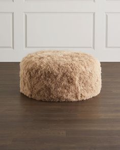 a large furry dog bed sitting on top of a hard wood floor next to a white wall