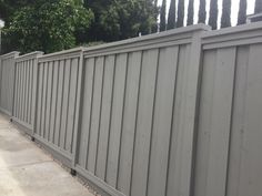 a long gray fence next to a sidewalk