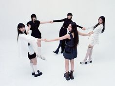 four young women in black and white outfits holding hands