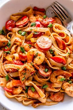 a bowl filled with pasta, shrimp and tomatoes