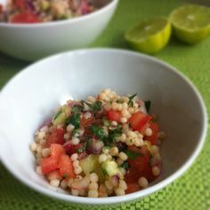 two bowls filled with food sitting on top of a green tablecloth next to lime slices