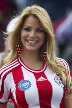 a woman in a red and white striped shirt smiles at the camera while wearing large earrings