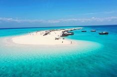 an island in the middle of the ocean with several boats docked at it's end