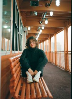 a woman sitting on top of a wooden bench next to a window in a building