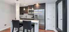 a kitchen with two bar stools next to an oven and refrigerator in the corner