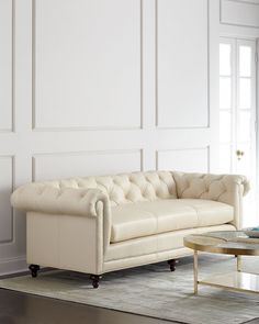 a living room with a white couch and coffee table in front of a large wall