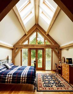 a bedroom with a bed, dresser and window in the ceiling is lit by sunlight streaming through the windows