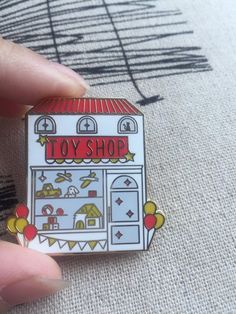 a hand holding a small toy shop pin