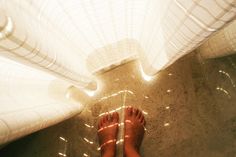 a person's feet standing on the floor in front of a white umbrella with lights